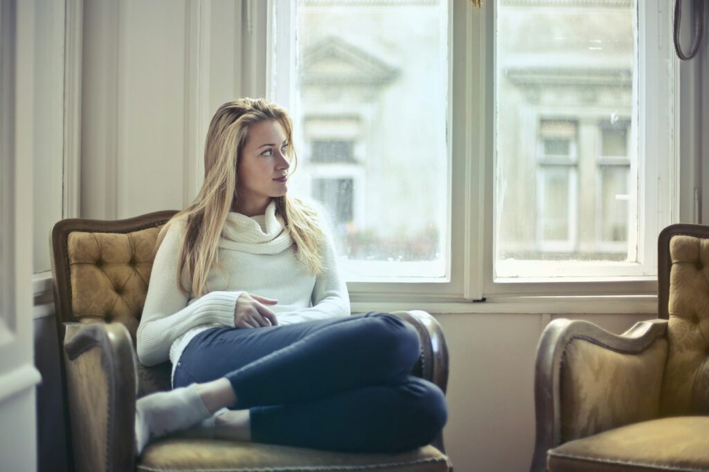 Woman sitting thoughtfully in an armchair by a window